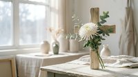 Wooden cross with white chrysanthemum flower on marble table in bright sunlit room with soft natural lighting creating peaceful spiritual atmosphere.