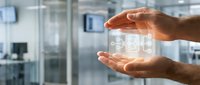 Hands holding glowing digital cube with data symbols in modern office environment, representing technology innovation and business solutions.