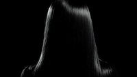 Dramatic black and white silhouette of straight long hair with glossy shine effect against dark background, highlighting smooth texture and professional styling.