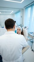 Male dermatologist consulting with female patient in modern cosmetic clinic during skincare treatment consultation session.