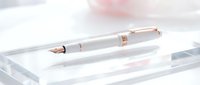 Elegant white fountain pen with rose gold accents resting on a clear glass surface, suitable for luxury branding, stationery design, and professional business materials.