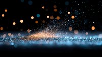 Magical glowing particles and bokeh lights creating ethereal atmosphere against dark background. Blue and orange sparkles floating in space with blurred effect.
