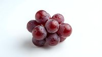 Fresh red grapes cluster with water droplets on white background, healthy organic fruit for nutrition and wellness concepts.