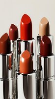 Collection of luxury lipsticks in warm autumn shades including red, brown, nude and orange tones arranged in silver tubes for beauty and cosmetics marketing.