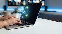 Professional using laptop with digital icons floating above screen representing modern technology and connectivity in office environment.