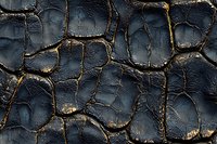 Dramatic dark cracked surface with golden light seeping through fissures creates abstract pattern of weathered texture, suitable for background designs and artistic projects.