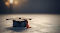 Graduation cap with red tassel on wooden surface with warm bokeh lighting background symbolizing academic achievement and educational success.