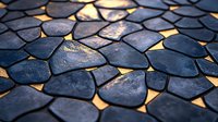 Illuminated dark stone mosaic pattern with golden light shining through gaps, creating dramatic contrast and texture on decorative paving surface.