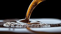 Pouring golden liquid stream creating splash and ripples on dark surface with dramatic lighting and macro photography detail. Suitable for beverage advertising.