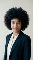 Professional African American businesswoman with natural afro hairstyle wearing dark blazer and white shirt against neutral background for corporate use.