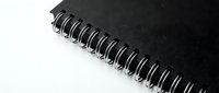 Black spiral notebook with metal binding on white background, suitable for stationery, office supplies, education, and business organization concepts.