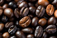 Fresh roasted coffee beans in dark brown and light brown colors showing natural variations and textures in macro photography closeup view.