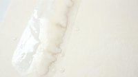 Fresh milk pouring into glass creating dynamic splash with droplets against clean white background for dairy and beverage advertising.