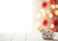 Wooden sheep figurine on white table with festive bokeh lights background, holiday decoration and seasonal celebration concept.