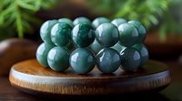 Polished green jade beads arranged on wooden plate with natural blurred background, showcasing luxurious mineral spheres for jewelry making and meditation.