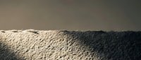 Textured sand dune surface with dramatic lighting and shadows creating natural patterns and ridges in desert landscape for backgrounds.
