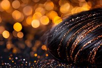 Macro shot of dark feather with water drops reflecting golden bokeh lights creating magical atmosphere. Glitter and sparkles add dreamy effect to nature detail.
