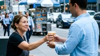 Woman and man shaking hands on urban street with blurred city background, business meeting or agreement between professionals outdoors.