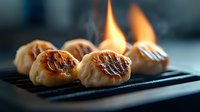 Flaming Asian dumplings on black cast iron pan with rising steam and dramatic lighting, close-up view showing crispy golden brown texture and caramelization.