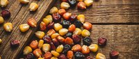Mixed colorful dried fruits and nuts scattered on rustic wooden table background for healthy snacking and cooking ingredients.
