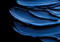Layered blue paper sheets creating abstract waves and curves against black background, artistic macro photography showing texture and depth for design projects.
