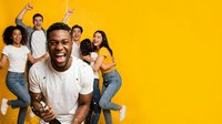 Diverse group of young adults celebrating success with raised fists and joyful expressions against bright yellow background. Team building, motivation, achievement.
