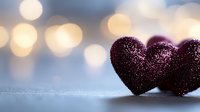 Purple glittery hearts on reflective surface against soft bokeh background. Romantic Valentine's day concept with sparkly decorative elements and dreamy lighting.