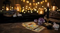 Mystical tarot card reading setup with crystals, candles and warm bokeh lights creating atmospheric fortune telling scene for spiritual guidance.