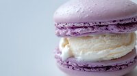 Purple macaron with white cream filling on light background, French pastry dessert for bakery menu, cafe advertising, food photography projects.