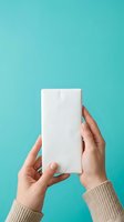 Hands holding blank white rectangular box against turquoise background for product packaging mockup and branding design.