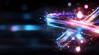 Glowing abstract light trails with sparkles and bokeh effects in blue and pink colors against dark background create futuristic motion design element.