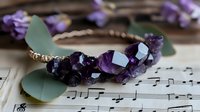 Elegant amethyst crystal bracelet with gold accents on sheet music background. Luxury gemstone jewelry for healing, meditation and fashion accessories.