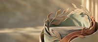 Elegant olive branch wreath resting on ancient stone pedestal with soft warm light and flowing fabric, evoking classical antiquity and timeless grace.