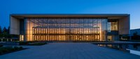 Modern glass office building with illuminated interior at dusk, contemporary corporate architecture with large windows and minimalist design for business concepts.