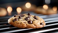 Freshly baked cookie with chocolate chips on striped napkin against warm bokeh lights, suitable for food photography, bakery marketing, and culinary content.