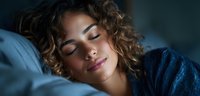 Young woman with curly hair sleeping peacefully in bed at night, relaxing in comfortable bedroom environment for wellness and rest concepts.