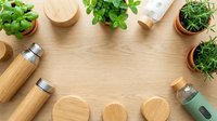 Eco-friendly bamboo kitchen utensils and fresh herbs arranged on wooden background with copy space for sustainable cooking and zero waste lifestyle.