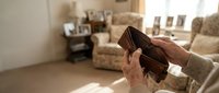 Empty wallet in hands showing financial hardship and money problems in cozy home interior with soft natural lighting for budgeting concepts.