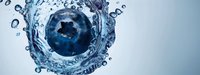 Fresh blueberry falling into clear water creating dynamic splash with droplets and bubbles on light blue background for healthy lifestyle concepts.