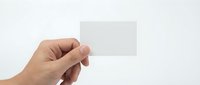 Hand holding blank white business card mockup on light background for branding and corporate identity design projects.