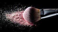 Makeup brush with pink powder explosion against black background, dynamic cosmetic motion capture showing professional beauty tool in action.