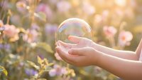 Gentle hands holding transparent soap bubble in blooming garden with soft pink flowers and warm golden sunlight creating dreamy magical atmosphere.