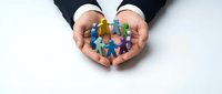 Business professional hands protecting diverse team of colorful paper cutout figures representing unity, teamwork and inclusion in corporate environment.