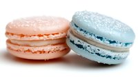 Two colorful French macarons with cream filling on white background, pink and blue pastry cookies isolated for bakery menu design and culinary projects.