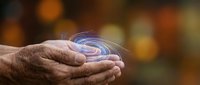 Elderly hands cupping glowing blue energy spiral with warm bokeh background representing healing, spirituality, and mystical power concepts.