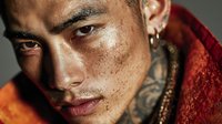 Young tattooed Asian man with facial piercings and freckles in red hoodie portrait for fashion and lifestyle concepts.