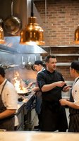 Professional chef team working together in modern commercial kitchen with copper pendant lights and brick walls during busy service.