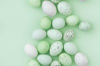 Decorative speckled Easter eggs in mint green and white colors scattered on pastel mint background, flat lay composition for spring holiday designs.