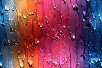 Colorful rainbow gradient background with water drops on glass creating abstract pattern. Natural light refraction through condensation makes vibrant artistic effect.