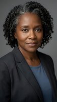 Professional African American businesswoman with curly gray hair in dark suit jacket and blue shirt against neutral background for corporate headshot.